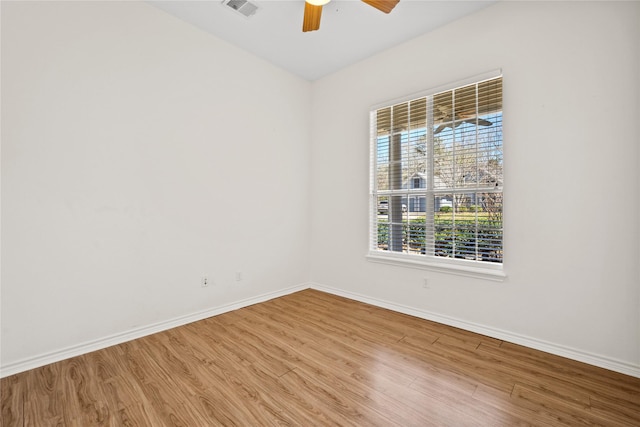 spare room featuring a ceiling fan, visible vents, baseboards, and wood finished floors