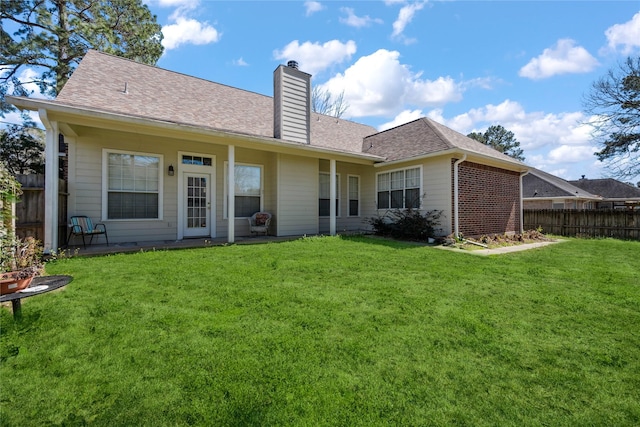 back of house with a yard, a shingled roof, a chimney, and fence