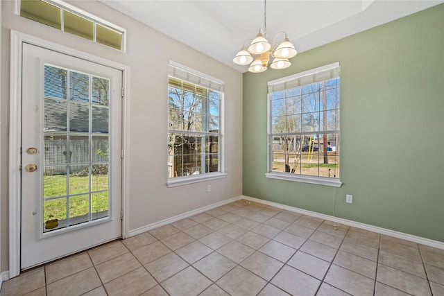 unfurnished dining area with an inviting chandelier, tile patterned flooring, baseboards, and a tray ceiling