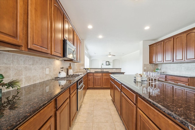 kitchen with sink, light tile patterned floors, appliances with stainless steel finishes, ceiling fan, and decorative backsplash