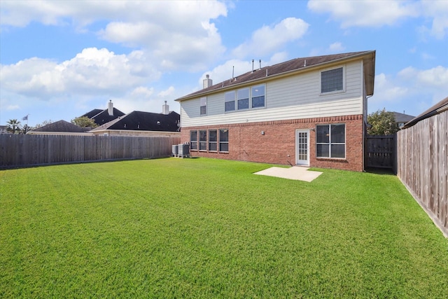 back of property with central AC unit, a patio area, and a lawn