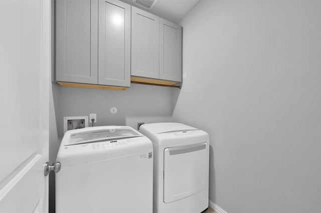 washroom featuring cabinets and washer and clothes dryer