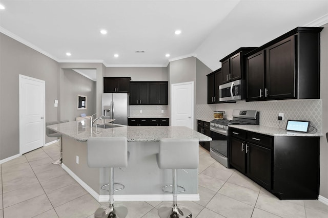 kitchen featuring stainless steel appliances, light tile patterned flooring, a breakfast bar area, and a center island with sink