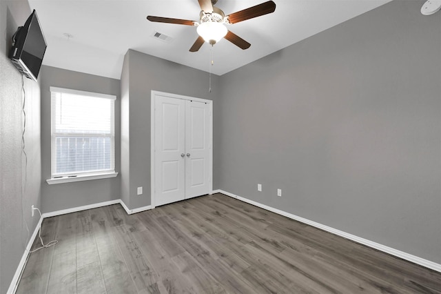 unfurnished bedroom featuring hardwood / wood-style flooring, ceiling fan, and a closet