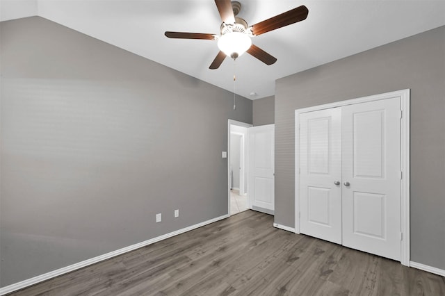 unfurnished bedroom featuring vaulted ceiling, ceiling fan, hardwood / wood-style floors, and a closet