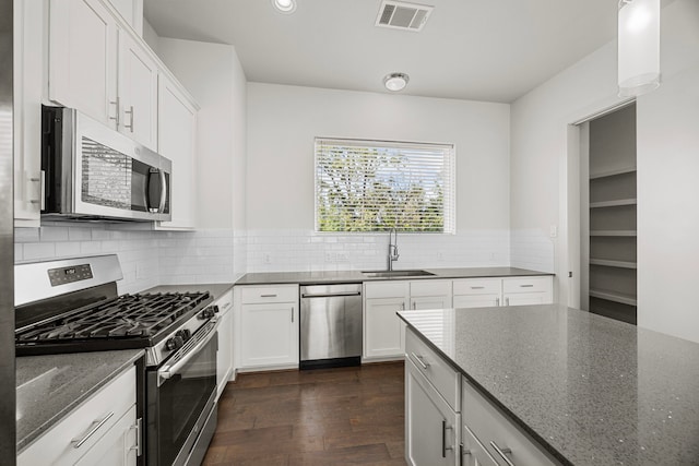 kitchen featuring sink, white cabinetry, dark stone countertops, appliances with stainless steel finishes, and dark hardwood / wood-style floors