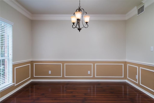 spare room with crown molding, dark hardwood / wood-style flooring, and a chandelier