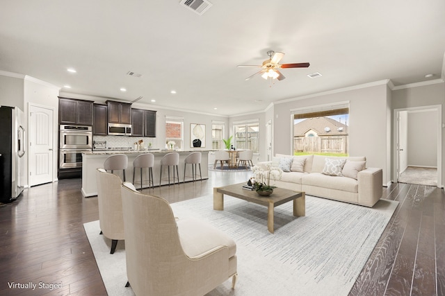 living room with crown molding, dark wood-type flooring, and ceiling fan