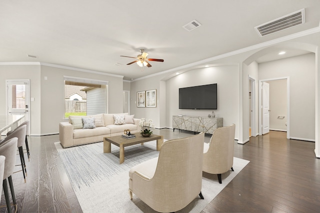 living room featuring dark hardwood / wood-style flooring, crown molding, and ceiling fan