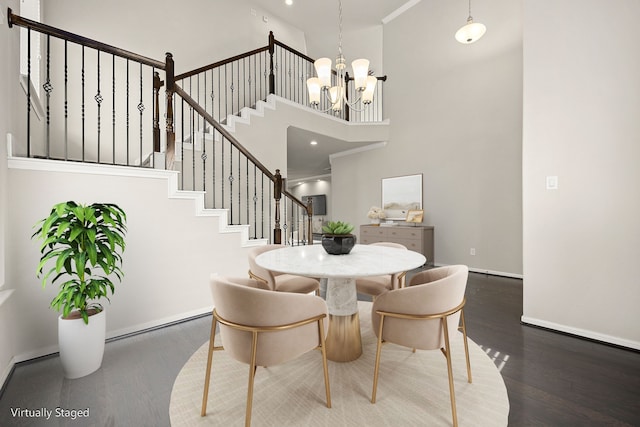 dining area with crown molding, a towering ceiling, an inviting chandelier, and dark hardwood / wood-style flooring