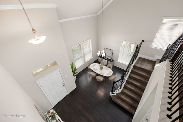 interior space with a high ceiling, ornamental molding, and wood-type flooring