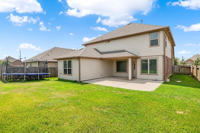 rear view of property featuring a yard, a patio area, and a trampoline