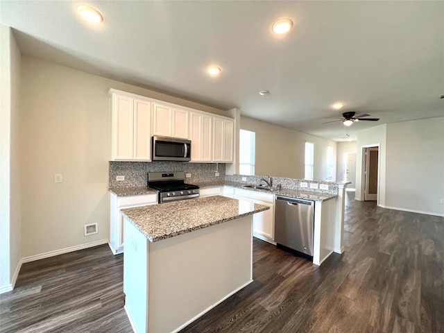 kitchen with sink, white cabinetry, a center island, dark hardwood / wood-style floors, and stainless steel appliances