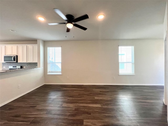 unfurnished living room featuring dark hardwood / wood-style flooring, ceiling fan, and a healthy amount of sunlight