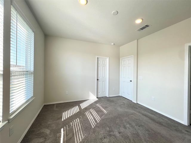 spare room featuring dark colored carpet