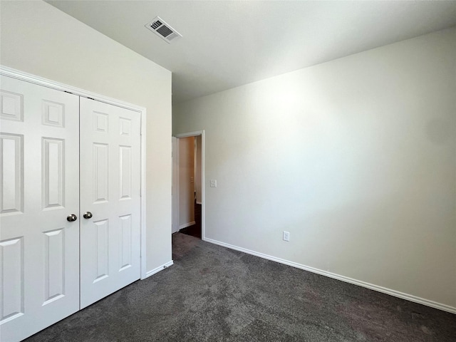 unfurnished bedroom featuring a closet and dark colored carpet