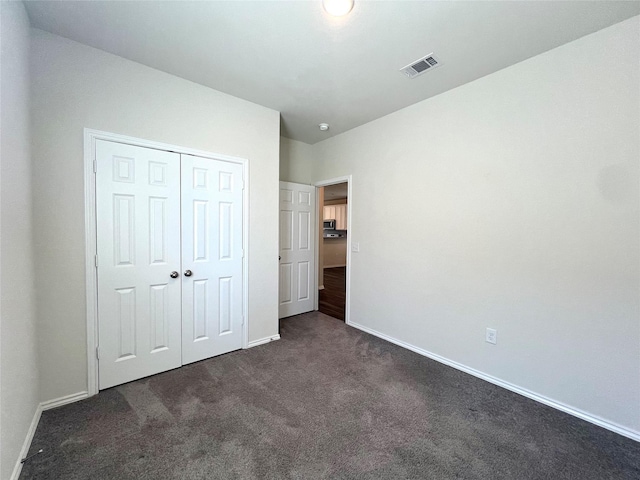 unfurnished bedroom featuring dark carpet and a closet