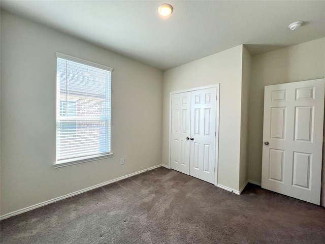 unfurnished bedroom featuring a closet and dark colored carpet