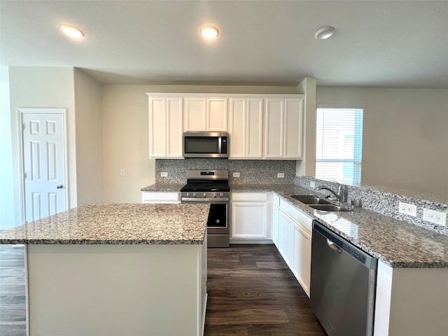 kitchen with stainless steel appliances, white cabinetry, a kitchen island, and sink