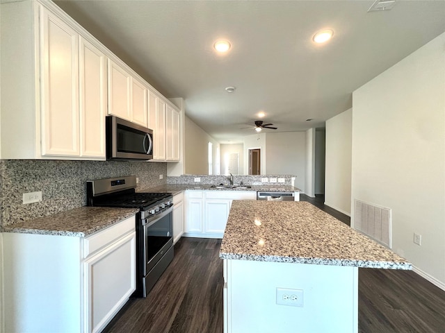 kitchen with white cabinetry, sink, a center island, kitchen peninsula, and stainless steel appliances