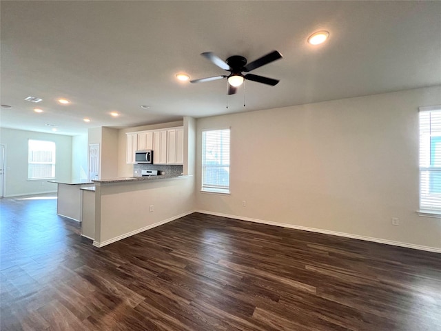 kitchen with white cabinetry, dark hardwood / wood-style flooring, kitchen peninsula, and plenty of natural light