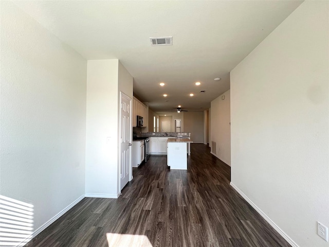 kitchen with sink, dark wood-type flooring, stainless steel range, white cabinets, and a kitchen island