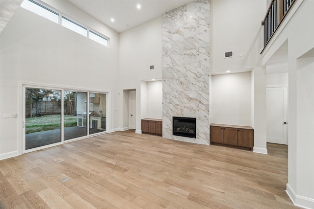 unfurnished living room featuring a premium fireplace and light hardwood / wood-style floors