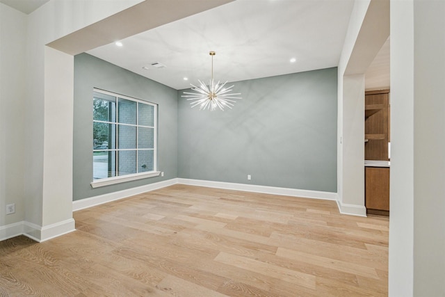 empty room featuring light hardwood / wood-style flooring and a notable chandelier