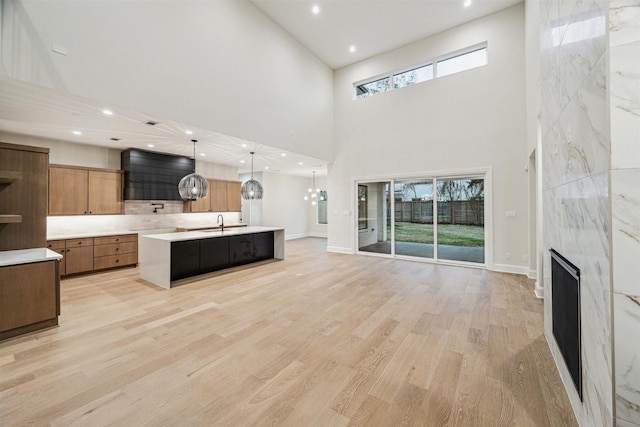 living room featuring a notable chandelier, light hardwood / wood-style flooring, a premium fireplace, and plenty of natural light