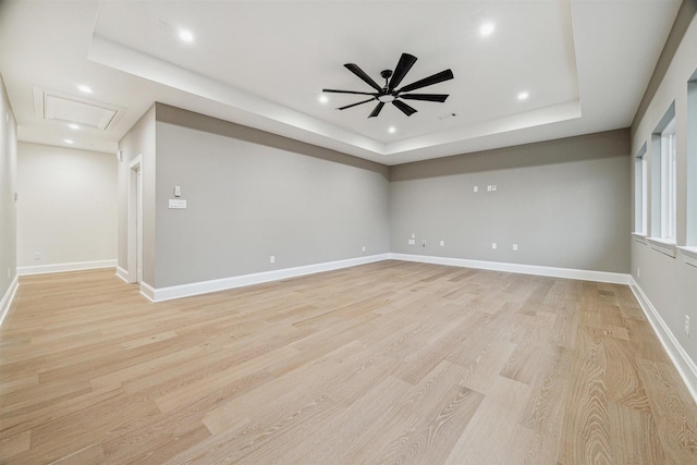 empty room featuring a tray ceiling, light hardwood / wood-style flooring, and ceiling fan