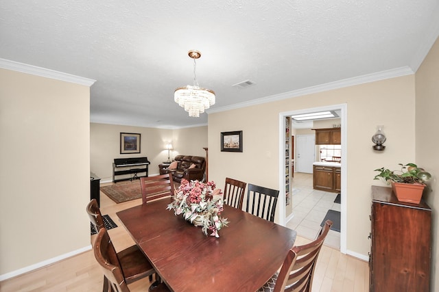 dining space featuring a notable chandelier, crown molding, and a textured ceiling