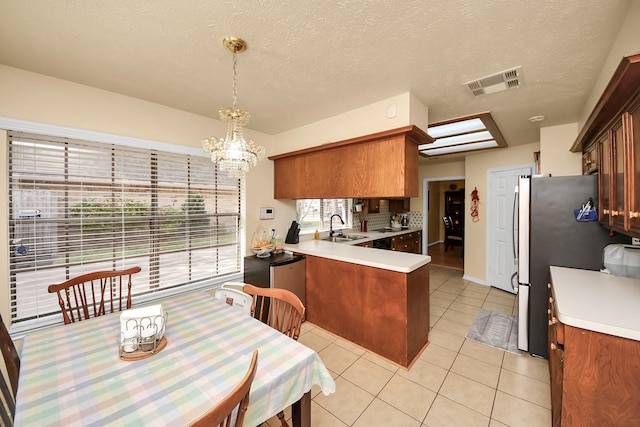 kitchen featuring sink, hanging light fixtures, light tile patterned floors, kitchen peninsula, and an inviting chandelier