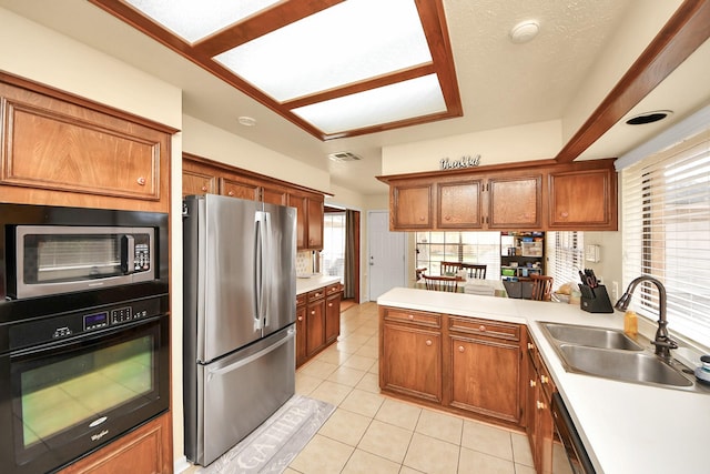 kitchen with light tile patterned floors, kitchen peninsula, sink, and black appliances