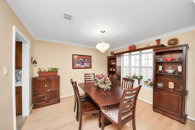 dining room with an inviting chandelier, crown molding, and light wood-type flooring