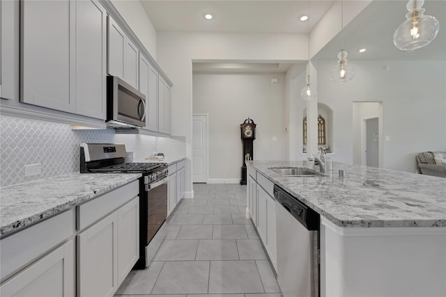 kitchen with light tile patterned floors, stainless steel appliances, light stone counters, and backsplash