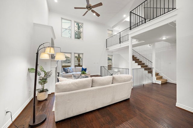 living room featuring dark hardwood / wood-style flooring, a towering ceiling, and ceiling fan