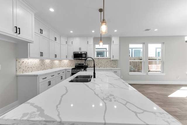 kitchen featuring decorative light fixtures, sink, white cabinets, light stone counters, and stainless steel appliances