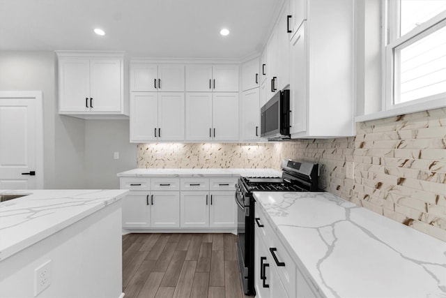 kitchen featuring white cabinetry, appliances with stainless steel finishes, light stone countertops, and backsplash