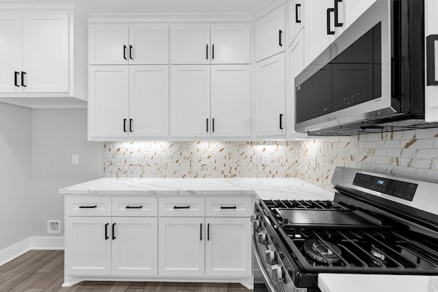 kitchen featuring light stone counters, tasteful backsplash, hardwood / wood-style flooring, stainless steel appliances, and white cabinets