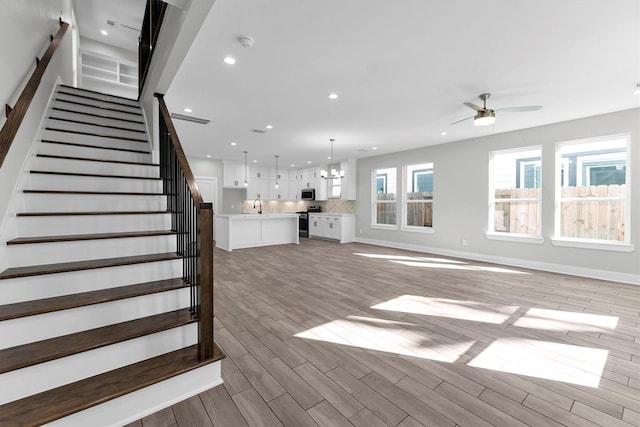 stairway with ceiling fan with notable chandelier, sink, and hardwood / wood-style floors