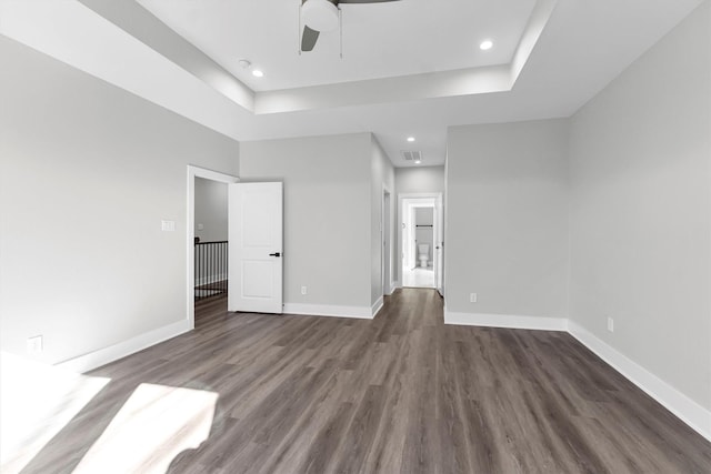 interior space featuring dark wood-type flooring, ceiling fan, and a tray ceiling