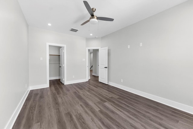 unfurnished bedroom featuring ceiling fan, dark hardwood / wood-style flooring, a closet, and a spacious closet