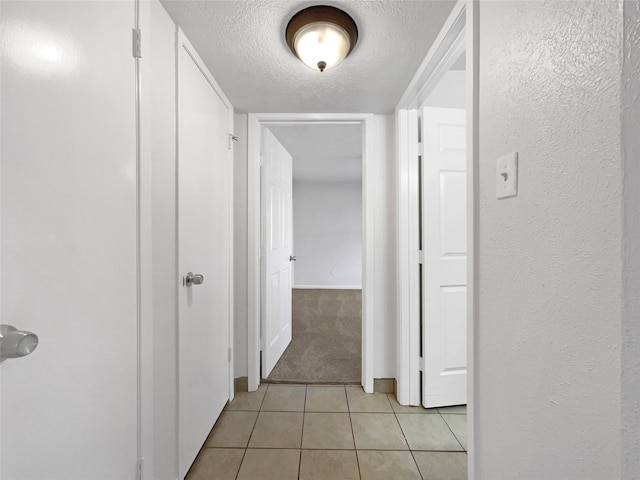 hall with light tile patterned flooring and a textured ceiling