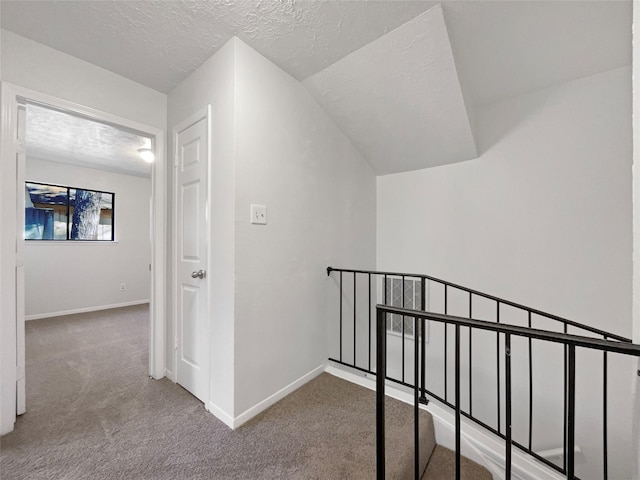 hall with lofted ceiling, a textured ceiling, and carpet