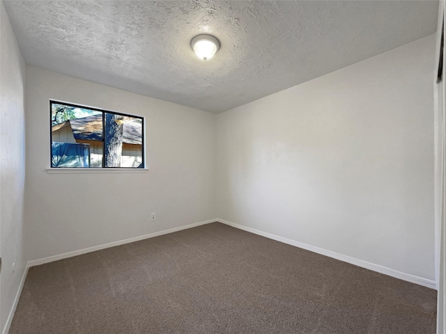 unfurnished room featuring dark carpet and a textured ceiling