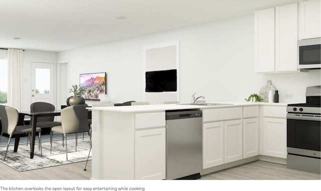 kitchen with stainless steel appliances, kitchen peninsula, sink, and white cabinets