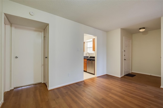 spare room featuring sink, a textured ceiling, and light hardwood / wood-style floors