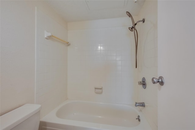 bathroom featuring a textured ceiling, toilet, and tiled shower / bath