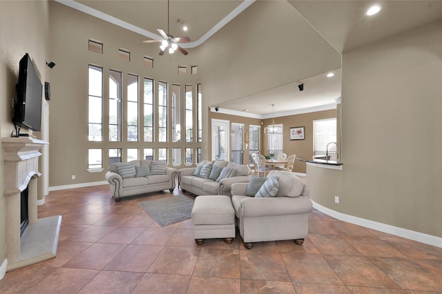 living room with light tile patterned floors, crown molding, ceiling fan, a towering ceiling, and a high end fireplace