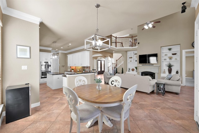 dining room with light tile patterned flooring, ceiling fan with notable chandelier, sink, a high ceiling, and crown molding